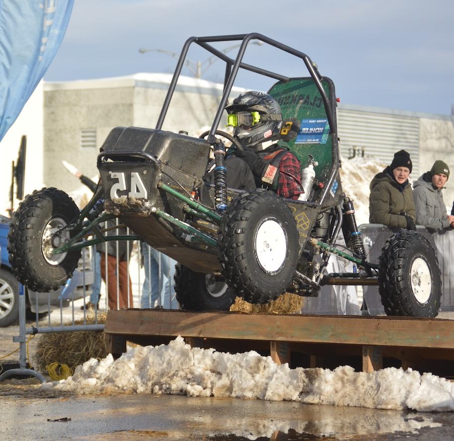 Baja SAE car over a jump with snow on the ground